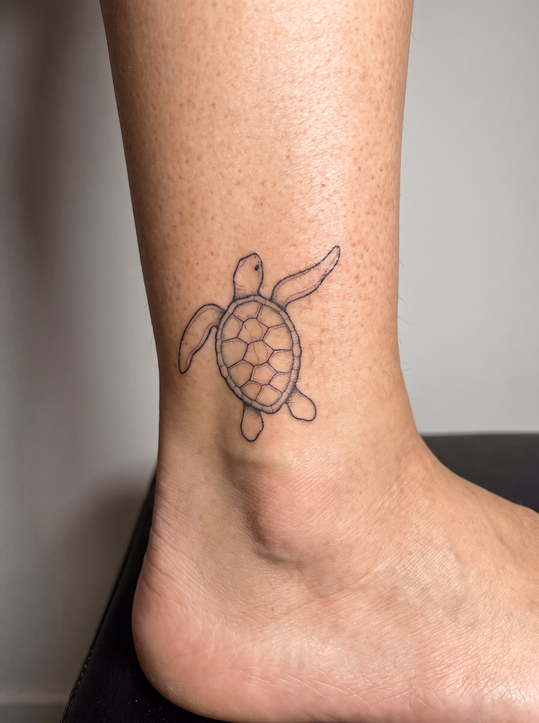 Small sea turtle tattoo design with fine line shell details, swimming flippers, and subtle dotwork